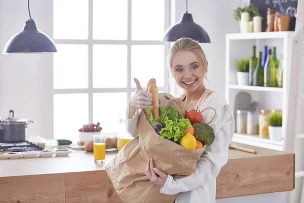 野菜提訴権と食料品の買い物袋を保持している若い女性 — ストック写真