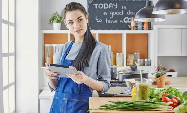 Happy woman looking recipe tablet kitchen reading cooking