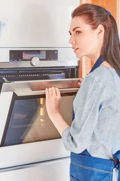 Beautiful woman in the kitchen, waiting with the front of the o