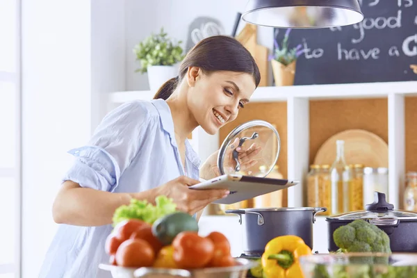 Imagem de uma jovem menina bonita de pé na cozinha e é coo — Fotografia de Stock