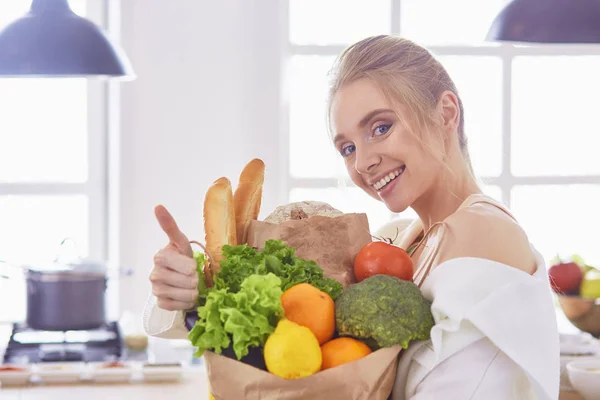 Bakkal alışveriş çantası ile sebze standi tutan genç kadın — Stok fotoğraf
