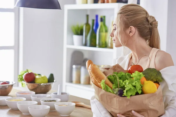 野菜提訴権と食料品の買い物袋を保持している若い女性 — ストック写真