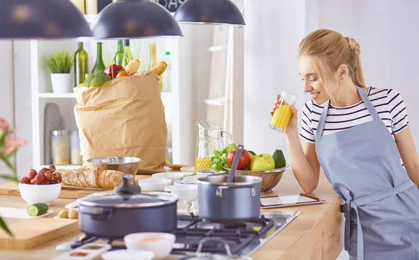 Девушка за столом на кухне со стаканом апельсинового соуса — стоковое фото
