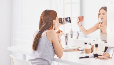 İnanılmaz genç kadın ayna önünde makyaj yapıyor. Portra