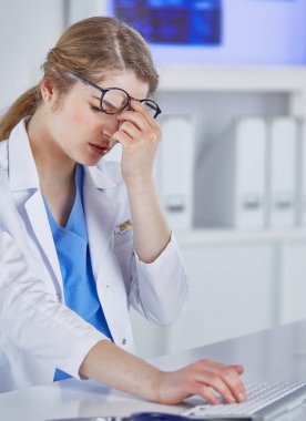 Genç kadın doktor bilgisayar ile çalıştıktan sonra yorgun