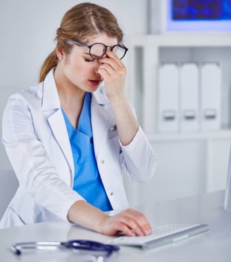 Genç kadın doktor bilgisayar ile çalıştıktan sonra yorgun