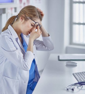 Genç kadın doktor bilgisayar ile çalıştıktan sonra yorgun