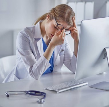 Genç kadın doktor bilgisayar ile çalıştıktan sonra yorgun