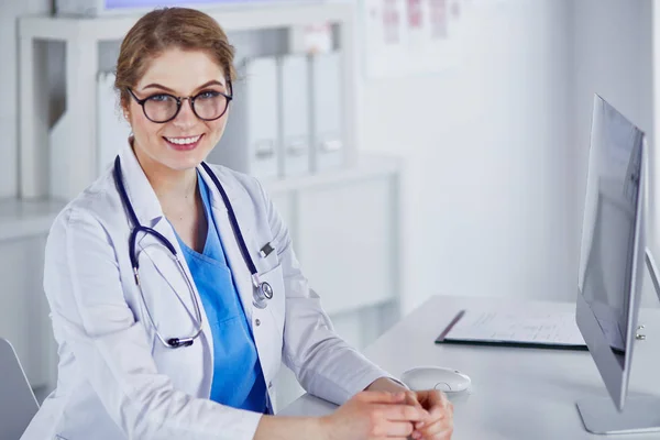 Masada oturan gülümseyen güzel genç bayan doktor. — Stok fotoğraf