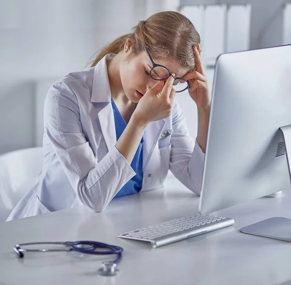 Νεαρή γυναίκα γιατρός κουρασμένη μετά την εργασία με τον υπολογιστή — Φωτογραφία Αρχείου