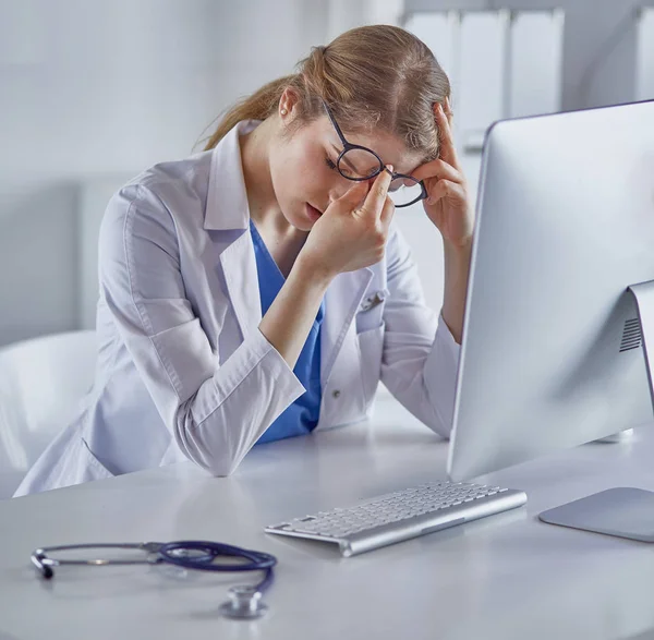 Genç kadın doktor bilgisayar ile çalıştıktan sonra yorgun