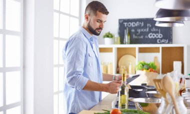 Gülümseyen ve kendinden emin şef büyük mutfakta duruyor.