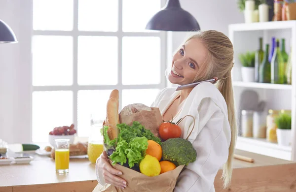 Junge Frau hält Einkaufstüte mit Gemüse in der Küche — Stockfoto