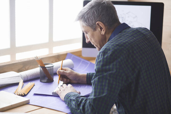 Плотник-инженер, работающий над проектом ноутбука и эскиза
