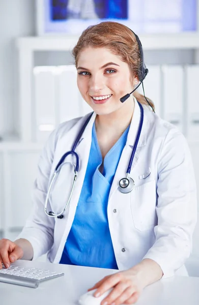 Retrato de un joven médico feliz sonriente con auriculares en la oficina — Foto de Stock