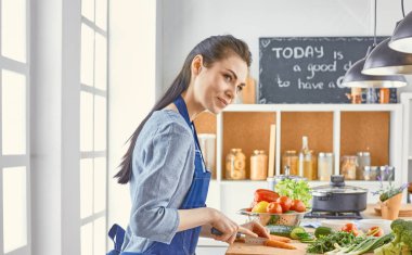 Mutlu kadın yemek tarifi arayan tablet mutfakta yemek yapıyor.