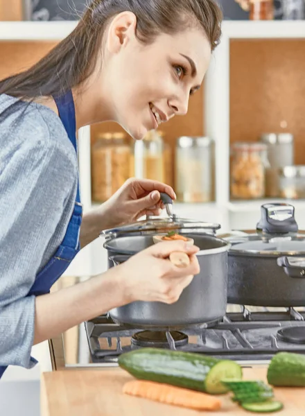Hermosa chica está degustando comida y sonriendo mientras se cocina en kit — Foto de Stock