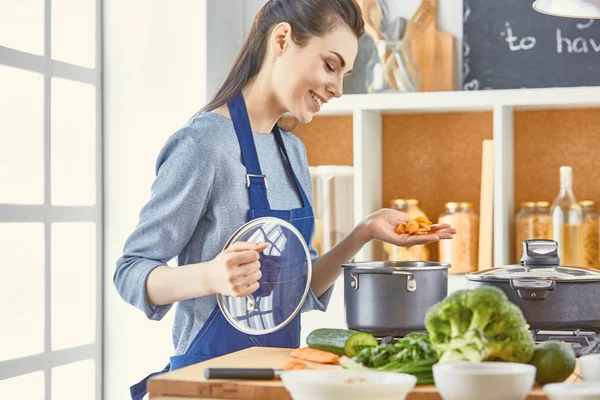 Hermosa chica está degustando comida y sonriendo mientras se cocina en kit — Foto de Stock