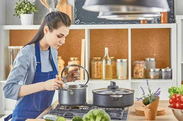 Beautiful girl is tasting food and smiling while cooking in kit — Stock Photo, Image