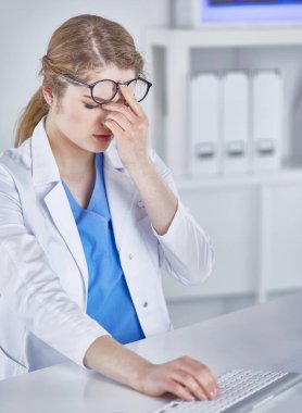 Genç kadın doktor bilgisayar ile çalıştıktan sonra yorgun