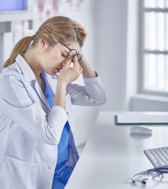 Genç kadın doktor bilgisayar ile çalıştıktan sonra yorgun