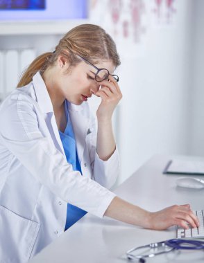 Genç kadın doktor bilgisayar ile çalıştıktan sonra yorgun