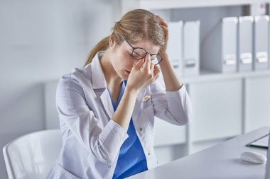 Genç kadın doktor bilgisayar ile çalıştıktan sonra yorgun