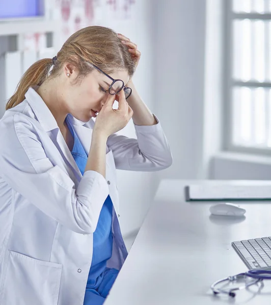 Genç kadın doktor bilgisayar ile çalıştıktan sonra yorgun