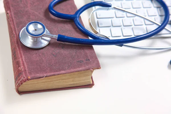 Medicinska stetoskop med gamla böcker och laptop på en tabell — Stockfoto