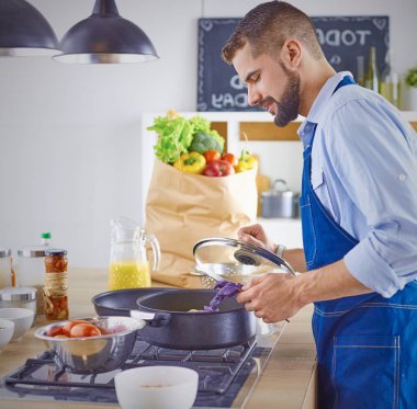 Gülümseyen ve kendinden emin şef büyük mutfakta duruyor.