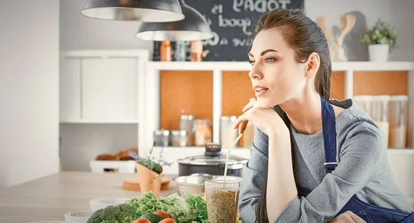 Glückliche junge Frau in der Küche mit frischem Gemüse auf dem Tisch — Stockfoto