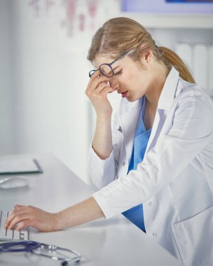 Genç kadın doktor bilgisayar ile çalıştıktan sonra yorgun