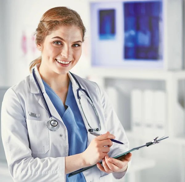 Młody kobieta lekarz stoi z deska z schowek szczęśliwy — Zdjęcie stockowe
