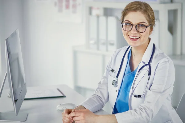 Masada oturan gülümseyen güzel genç bayan doktor. — Stok fotoğraf