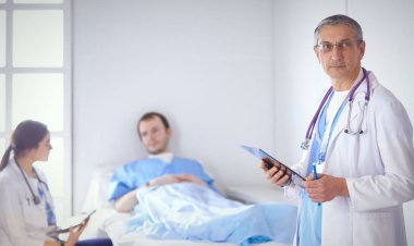 Doktor stetoskop ile yatakta hasta kalp ritmini kontrol