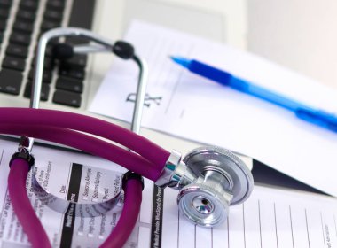 Beyaz ahşap bir masa üstünde a laptop yanında sağlık stetoskop