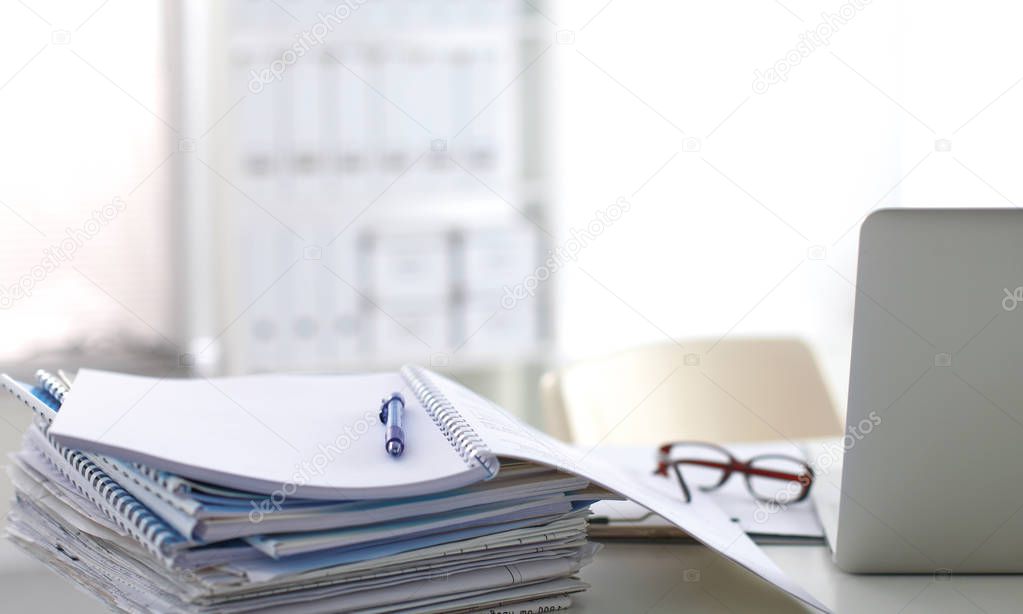 Laptop with stack of folders on table on white background