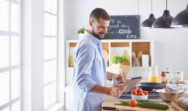 Gülümseyen ve kendinden emin şef büyük mutfakta duruyor.