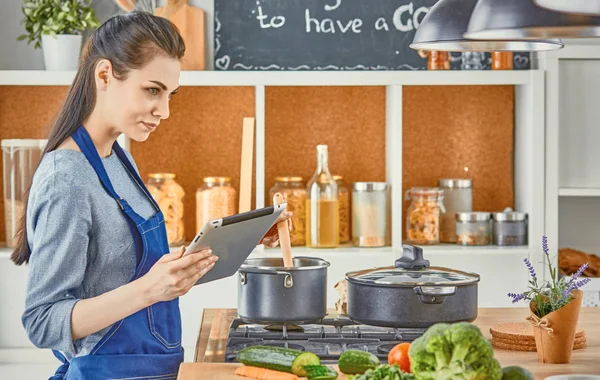 Happy woman looking recipe tablet kitchen reading cooking