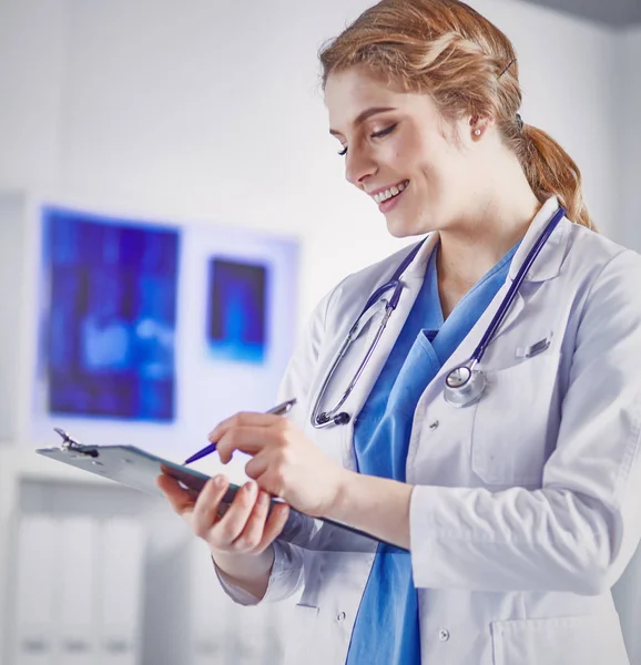 Jeune femme médecin est debout avec planche avec presse-papiers smilin — Photo