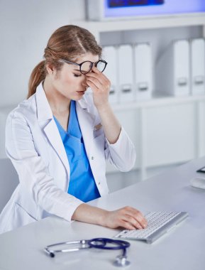 Genç kadın doktor bilgisayar ile çalıştıktan sonra yorgun
