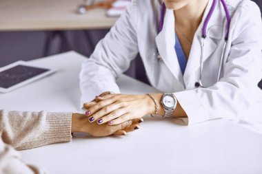 Kadın doktor hastayı sakinleştirir ve elini tutar