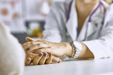 Kadın doktor hastayı sakinleştirir ve elini tutar