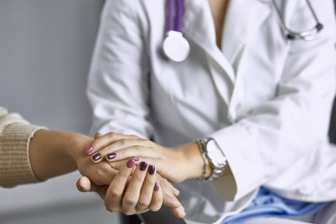 Kadın doktor hastayı sakinleştirir ve elini tutar