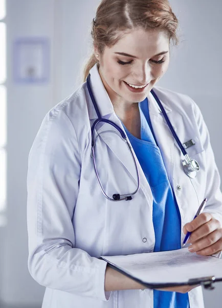 Giovane donna medico è in piedi con bordo con appunti smilin — Foto Stock