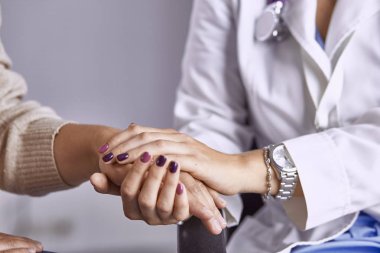 Kadın doktor hastayı sakinleştirir ve elini tutar