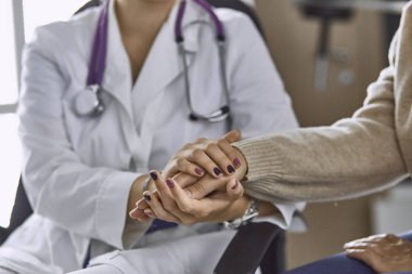 Kadın doktor hastayı sakinleştirir ve elini tutar