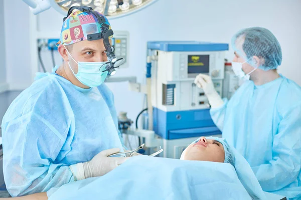 Mehrere Ärzte umgeben Patientin auf Operationstisch — Stockfoto