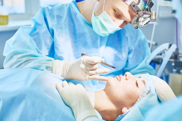 Varios médicos que rodean al paciente en la mesa de operaciones durante t — Foto de Stock