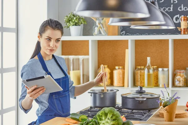 Happy woman looking recipe tablet kitchen reading cooking